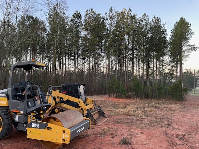 Excavator positioned on a forest access trail between tall trees on a clear sunny day